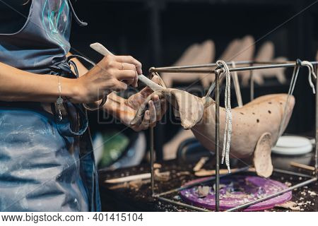 Close-up View Of Female Hands Gently Handling A Clay Whale In Workshop.