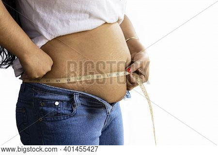 Mid Section Side View Of An Indian Woman Measuring Fat Belly With Tape On White Background