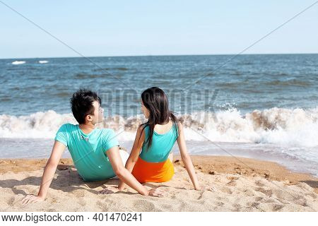 Couple Sitting On Seaside Watching Each Ohter