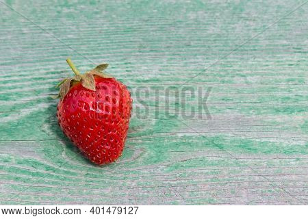 One Red Fresh Strawberry On Green Wooden Background