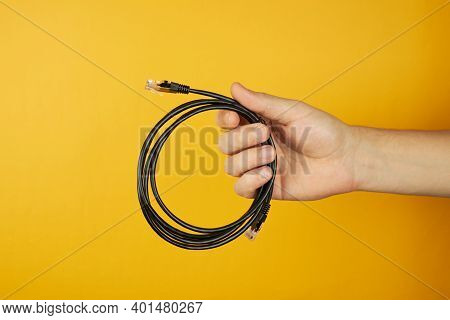 Concept Of Network, Internet, Communications. Hand Holds Cat 5e Utp Cable. Isolated On Yellow Backgr