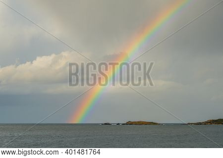 View Across The Mediterranean Sea Towards An Island And A Colurful Rainbow At Punta Caldanu Near Lum