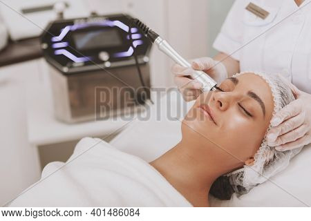 Young Beautiful Woman Visiting Osmetologist, Getting Skin Treatment. Cropped Shot Of A Professional 