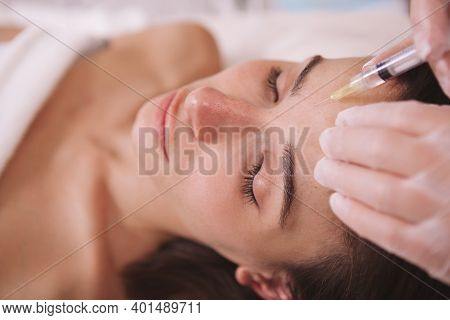 Close Up Of A Woman Getting Anti-wrinkle Filler Injections In Her Forehead. Female Client Receiving 