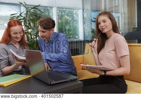 Attractive Female Entrepreneur Making Notes While Meeting With Business Team At Modern Office