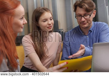 Team Of Designers Working On A Project Together, Using Laptop