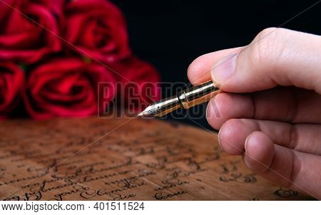 Fountain Pen In The Hand On Letter With Text And Red Roses Close Up