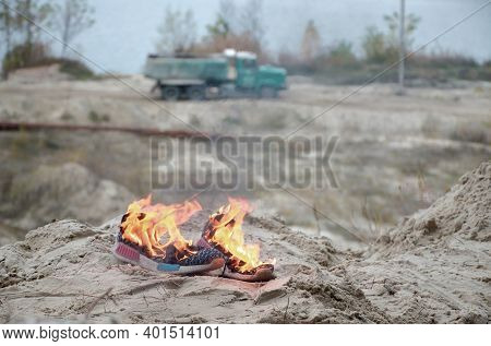 Burning Sports Sneakers Or Gym Shoes On Fire Stand On Sandy Beach Coast Close Up. Athlete Burned Out