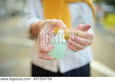 Senior Woman In Face Mask Using Sanitizer Because The Second Wave Of The Covid-19 Epidemic Began. Lo