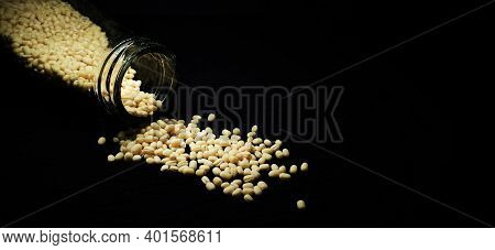 Closeup Of Urad Dal (white) In A Glass Container Spilled On A Isolated Black Background With Copy Sp
