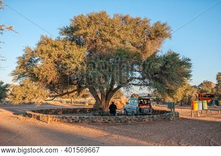 Sesriem, Namibia - June 22, 2012: A Camping Site Under A Large Camel-thorn Tree At Sesriem. One Pers
