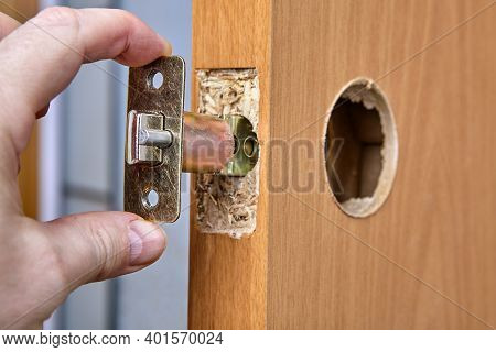 Carpenter Shoves Latch Assembly Of Door Knob Through The Edge Bore.