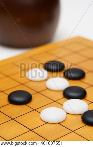 Black And White Baduk Stones On Wood Board On White Table