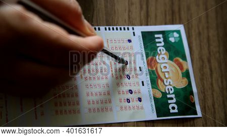 Salvador, Bahia, Brazil - January 2, 2021: Person Scoring Mega Sena Lottery Ticket In The City Of Sa