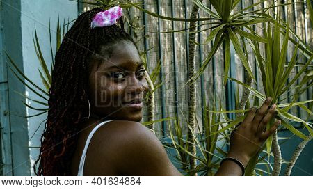 The Young African Woman Dressed In A White Dress Is Smiling As She Looks At The Camera,she Rests Her