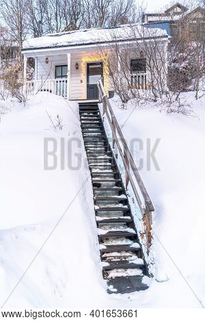 Outdoor Stairs On Snowy Slope Going Up To The Entrance Of Single Storey House