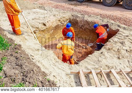 Workers Are Using Shovels To Set Up Level Foundation To Right Measures In Square Trench, Wooden Ladd