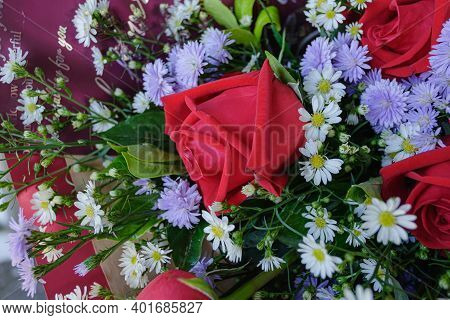 Close  Up Of Red Roses In A Bouquet That Has White Cutters And Purple Daisy Included.