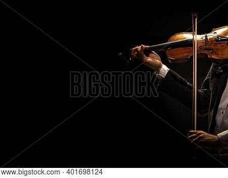 The Violinist Plays The Violin On A Dark Background.