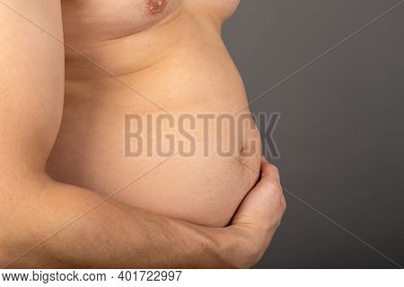 Close Up Picture Of Young Man\'s Bloated Stomach In Front Of Grey Background