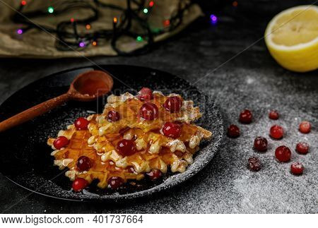Belgian Waffles On A Black Plate With Cranberries, Sprinkled With Powder And Honey. Dark Background 
