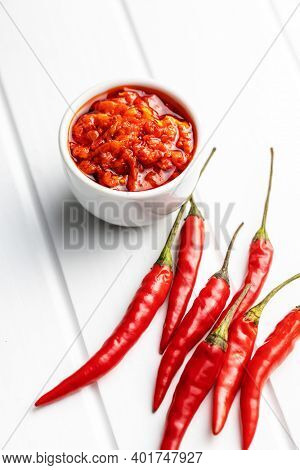 Red hot chili paste and chili pepper on white table.