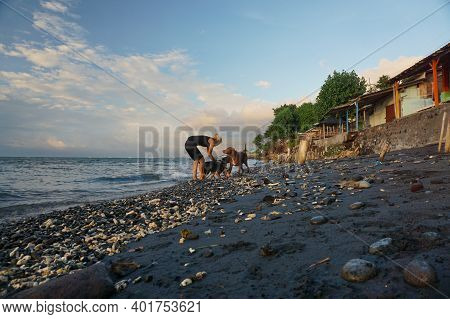 Banyuwangi, Indonesia - May 14, 2020 : A Woman Playing With The Dogs At Watudodol Beach Banyuwangi I