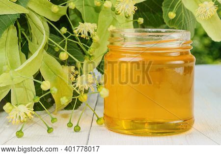 Jar Of Linden Honey And Flowering Linden On Wooden Table