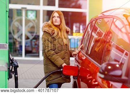 Young Caucasian Woman At Self-service Gas Station, Hold Fuel Nozzle And Refuel The Car With Petrol, 
