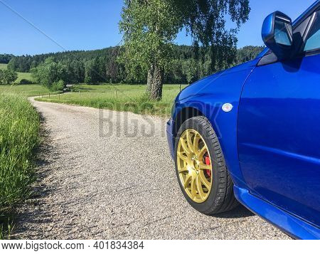 The Blue Youngtimer Sports Car With Golden Rims Is Standing On The Narrow Road And Is Ready To Drive