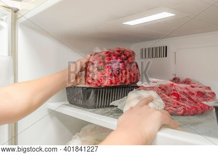 The Woman Takes Out A Bag Of Frozen Cherries From The Freezer.