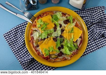 Pizza Hamburger With Meat Shashlik, Mustard, Lettuce, Cheese, Sauce. Food In A Yellow Plate On A Blu