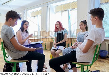 Female Teacher And Group Student Teenagers In The Classroom, Talking, Discussing School Projects