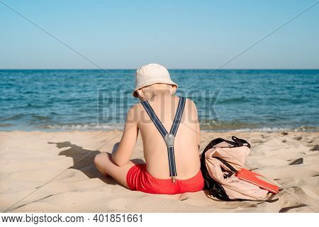 Happy Young Boy Reading A Book On A Sunny Dayl. Boy Sitting Sad With His Back At The Beach. Last Day