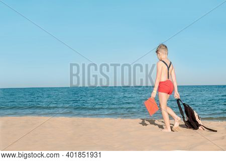 Happy Young Boy Reading A Book On A Sunny Dayl. Boy Sitting With His Back At The Beach. Last Day Of 