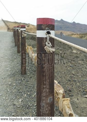 Fence Of Round Wooden Posts Attached With A Rope To Delimit The Path. High Mountain Trail Marking Wi