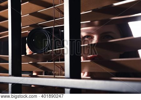 Private Detective With Camera Spying Near Window Indoors, Closeup