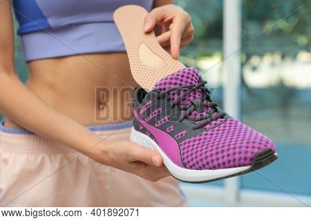 Woman Putting Orthopedic Insole Into Shoe Indoors, Closeup. Foot Care