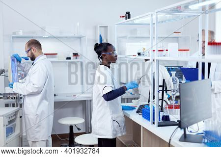 African Scientist Using Glass Flask In Sterile Microbiology Laboratory To Discover A Vacine. Multiet