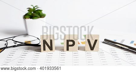 Net Present Value. Npv The Word On Wooden Cubes, Cubes Stand On A Reflective Surface, In The Backgro