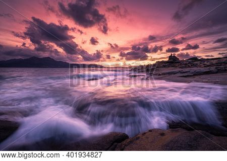 Beautiful Sunset Over An Ancient Genoese Tower As Waves Crash Onto The Rocky Coastline At Punta Cald