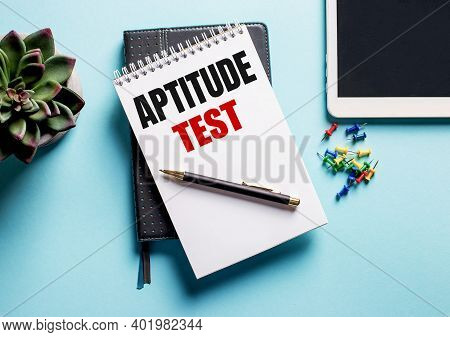 On A Light Blue Background, There Is A Potted Plant, A Tablet And A Weekly With The Text Aptitude Te