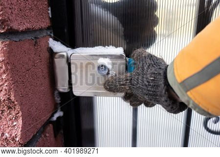 Man Hand Wearing Woolen Glove Opening A Frozen Lock .frozen Door Lock On The Street