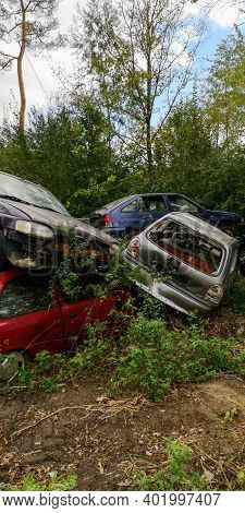 A Few Old Damaged Cars With Rust, With Broken Windows, Mangled, Piled Up.green Nature, Trees, Grass,