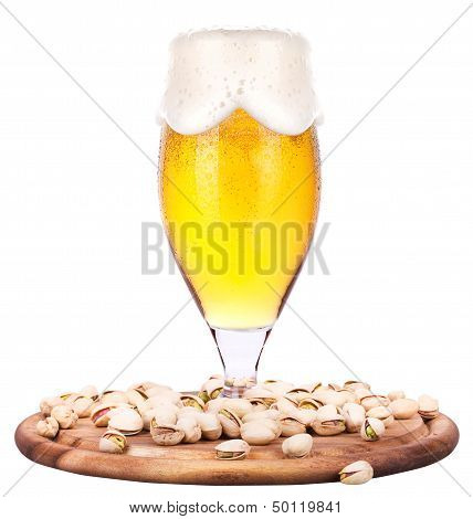 Frosty glass of light beer with pistachos