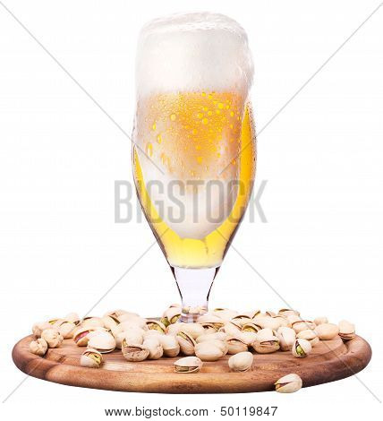 Frosty glass of light beer with pistachos
