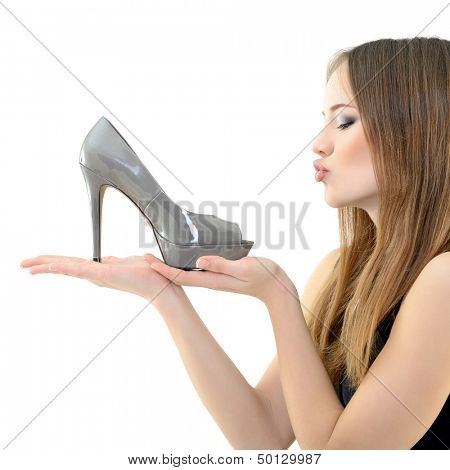 girl holding shoe in hand an looking with love on it, over white