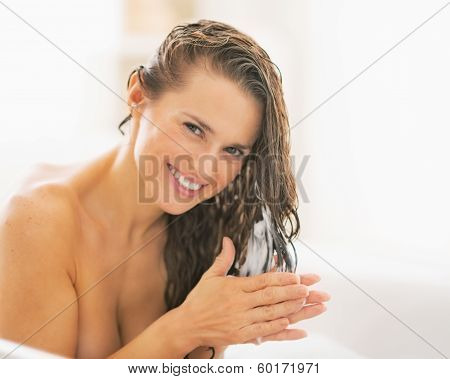 Happy Young Woman Applying Hair Conditioner