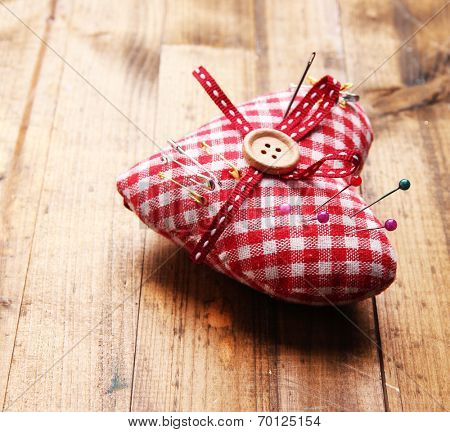 Fabric heart with color and safety pins on wooden background