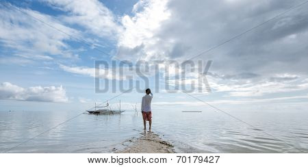 standing young man looks at horizon on beach